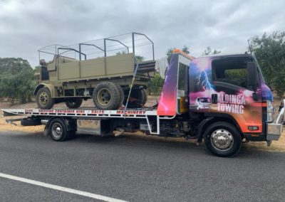 Tilt truck towing an ex army vehicle
