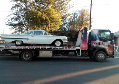 Tilt truck towing a classic American Car which is being towed for restoration