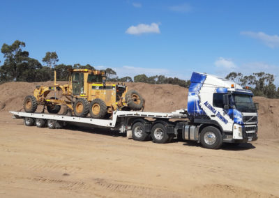Large Tilt tray truck transporting large roadwork machinery in Adelaide